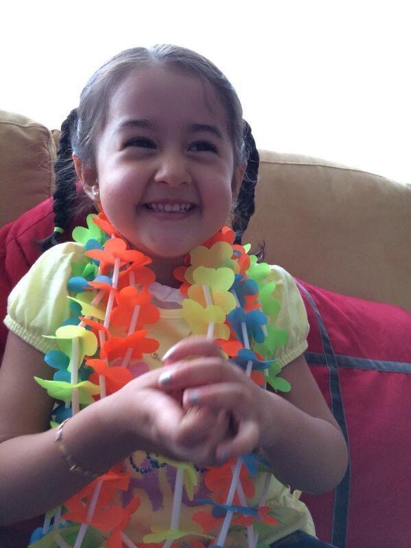 Isa de niña sonriendo con un collar de flores